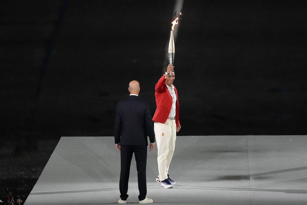 Torchbearer Zinedine Zidane passes the Olympic torch to Rafael Nadal, of Spain, during the open ...