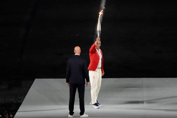Torchbearer Zinedine Zidane passes the Olympic torch to Rafael Nadal, of Spain, during the open ...