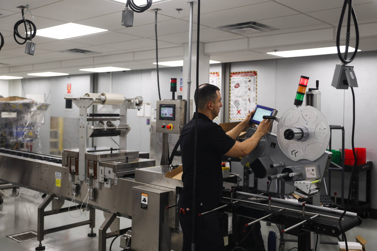 A worker helps install a new machine to assist in automating the food packing process for the M ...