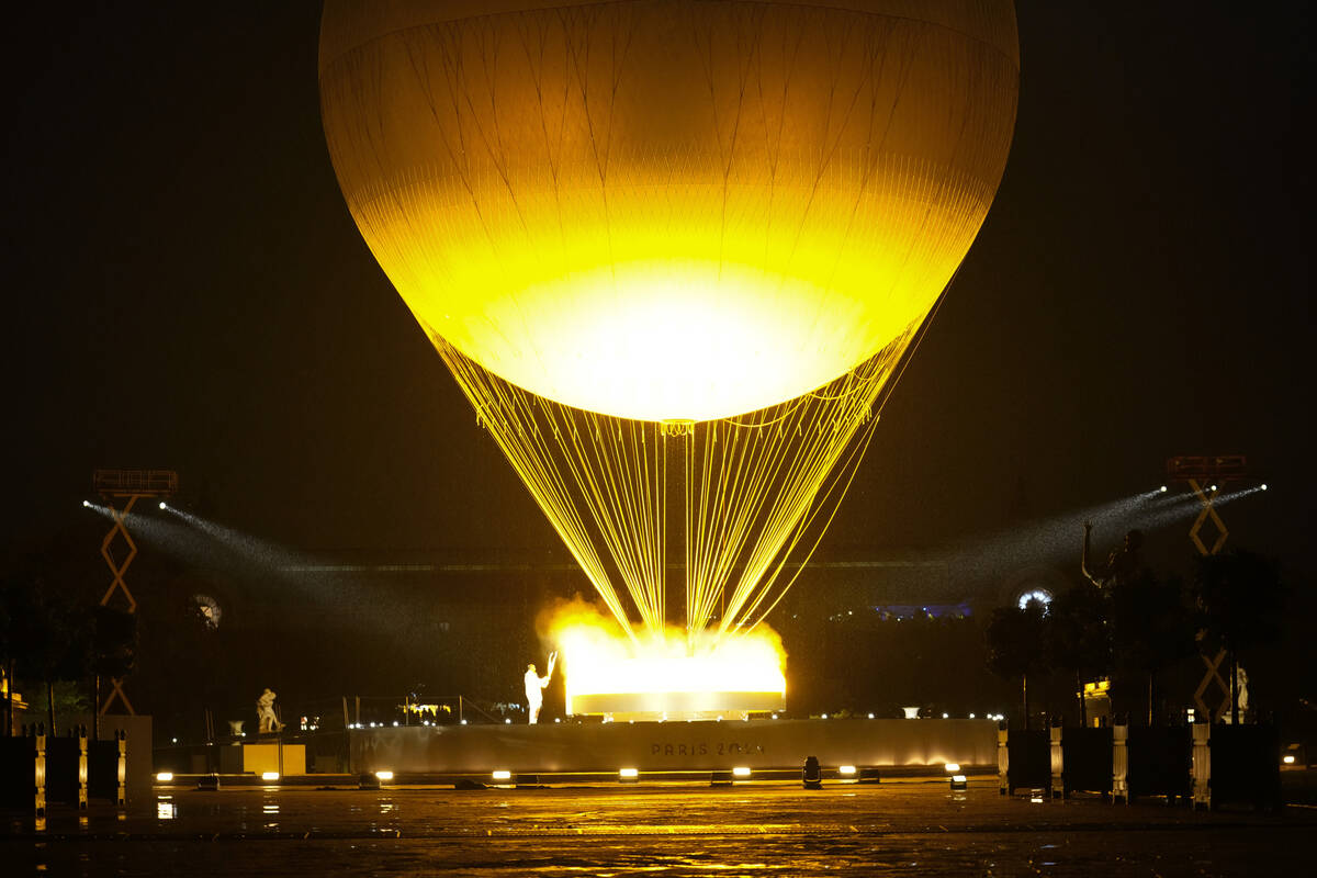 Teddy Riner and Marie-Jose Perec watch as the cauldron rises in a balloon in Paris, France, dur ...