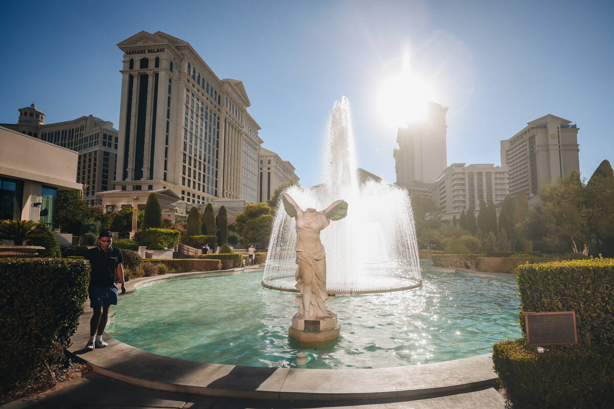 A tourist walks by the Caesars Palace fountains to keep cool as the sun beams down on Sunday, J ...