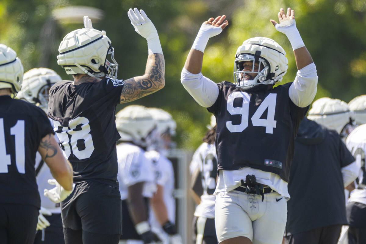 Raiders defensive tackle Christian Wilkins (94) gets pumped up with defensive end Maxx Crosby ( ...