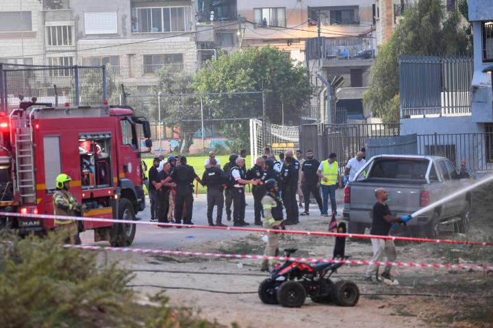 Israeli police officers and firefighters work at the site of a rocket attack in Majdal Shams, i ...