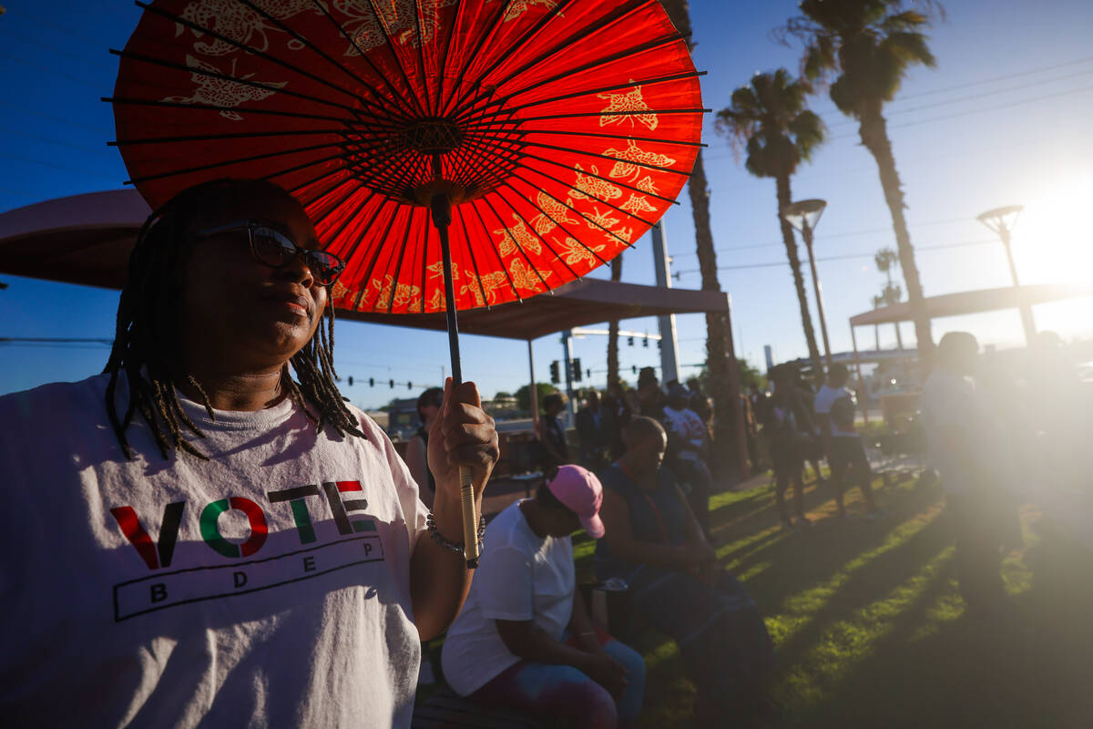 A mourner uses an umbrella to block out the sun during a vigil for Sonya Massey, a Black woman ...