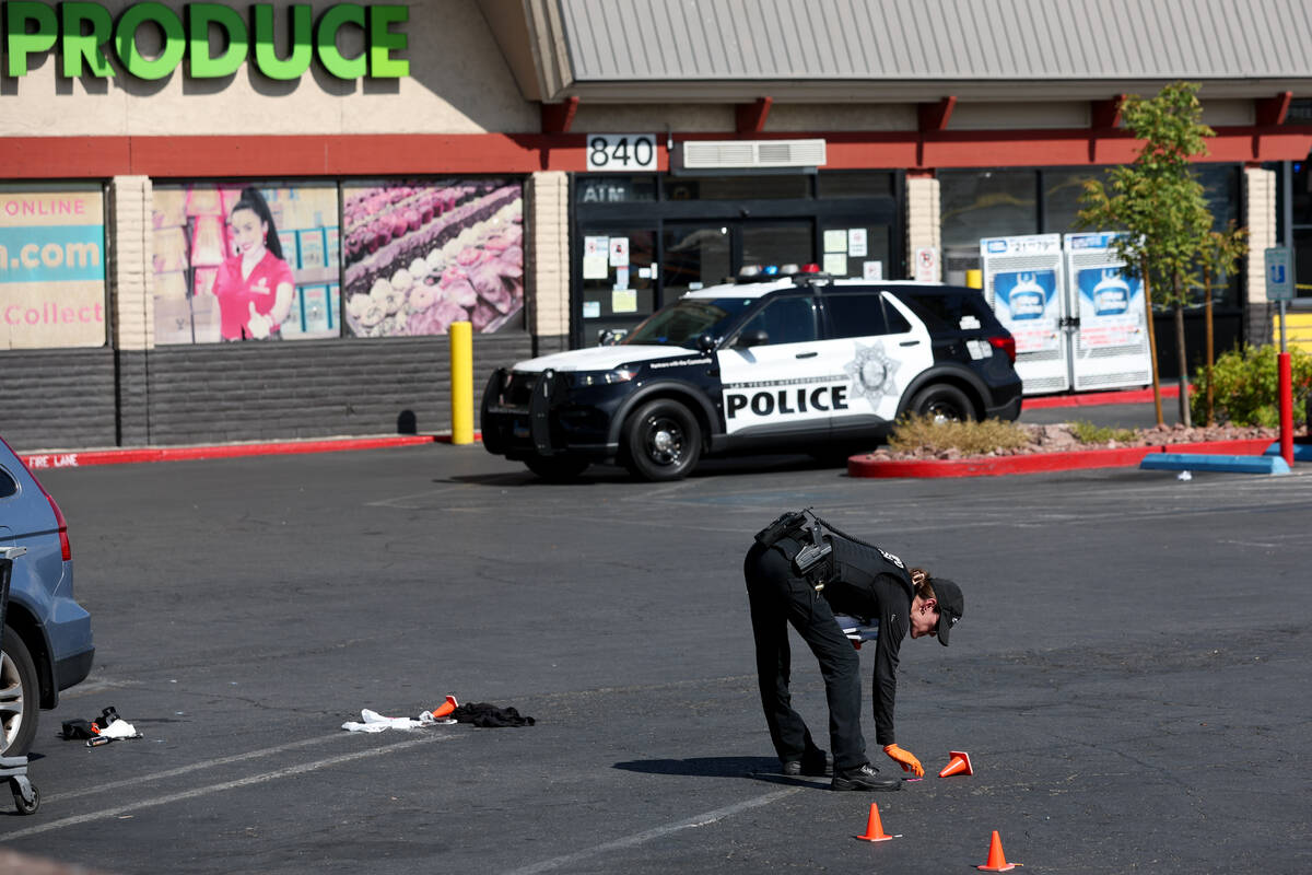 Metropolitan Police Department officers investigate a taped-off scene at a shopping center park ...