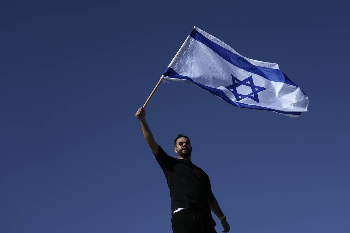 A protester waves the Israeli national flag in support of soldiers being questioned for detaine ...