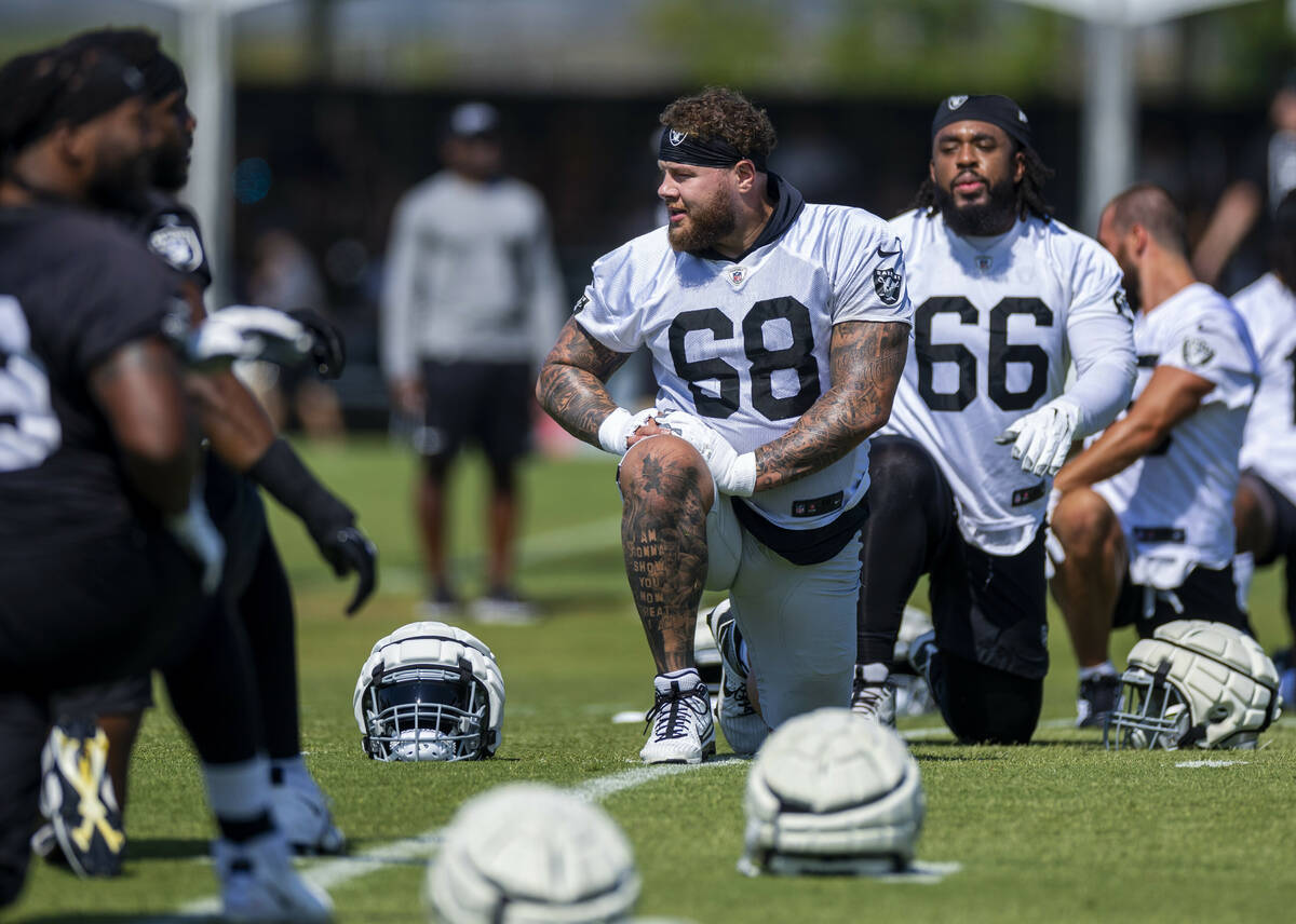 Raiders center Andre James (68) and guard Dylan Parham (66) join teammates in stretching during ...