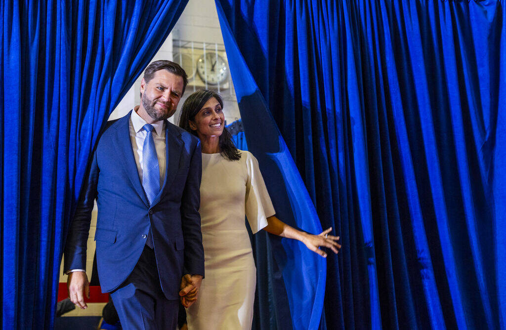 Ohio Senator JD Vance and his wife Usha look out from the side curtains as they arrive on stage ...