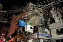 A man removes power cables near a destroyed building that was hit by an Israeli airstrike in th ...