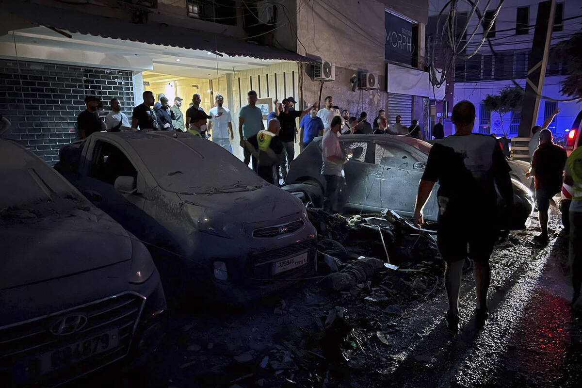 People inspect damaged cars in the southern suburbs of Beirut, Lebanon, Tuesday, July 30, 2024. ...