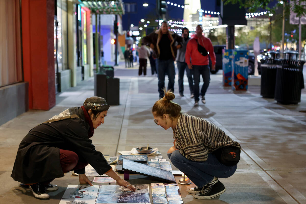 An artist shares their work with passersby on Main Street during First Friday on Friday, April ...