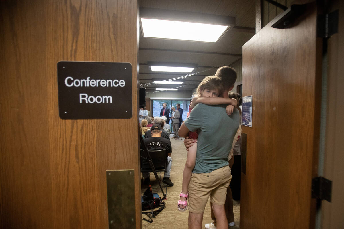 Daphne Thompson, 4, looks back while being held by her father Alex Thompson during a community ...