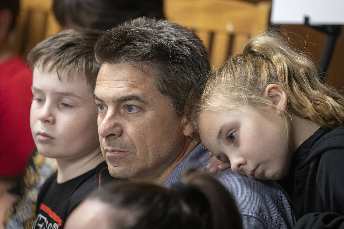 Joe Collins, center, sits with his children Nicholas, 10, left, and Elizabeth, 8, right, as the ...