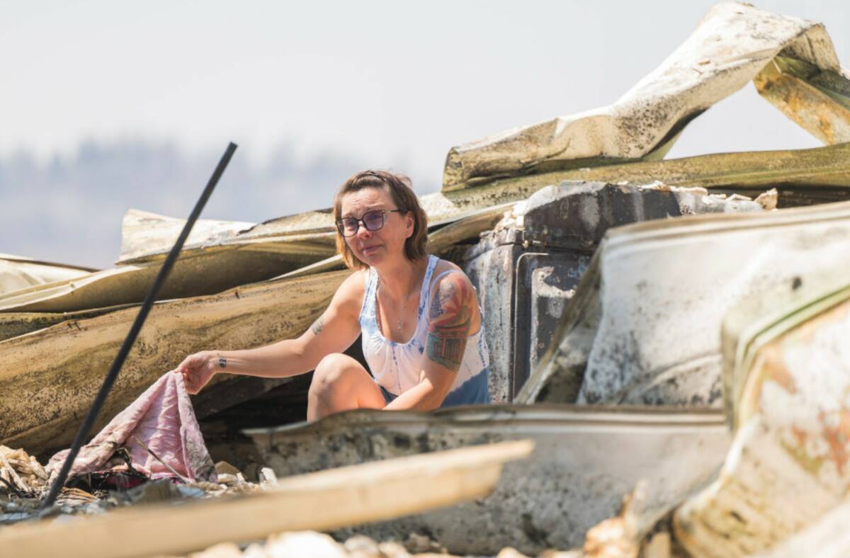 Andrea Blaylock becomes emotional as she sifts through the charred remains of her home that was ...