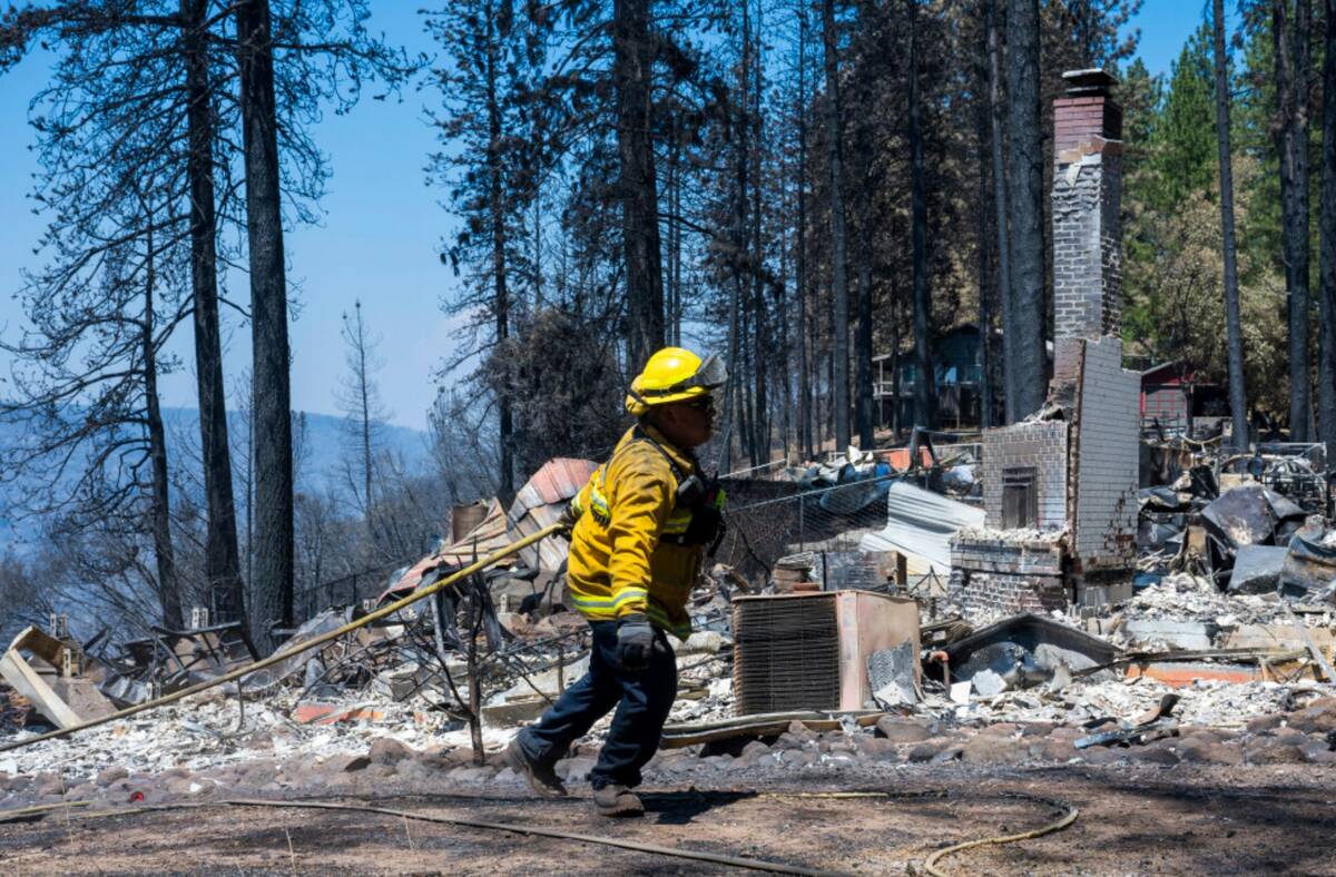 A firefighter walks by the remains of a home that was destroyed in the Park Fire near Forest Ra ...