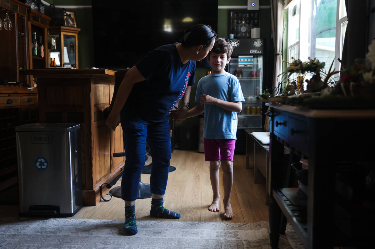 Caroline Ver, a registered behavior technician, guides Jakob Velez, 8, back to the kitchen for ...