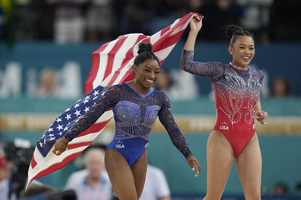 Simone Biles, left, celebrates with teammate Suni Lee, of the United States, after winning the ...