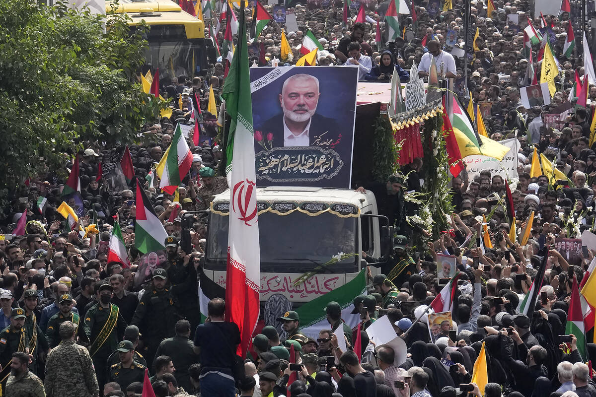 Iranians follow a truck, center, carrying the coffins of Hamas leader Ismail Haniyeh and his bo ...