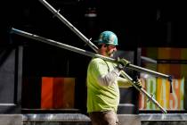 FILE - A construction worker carries scaffolding parts on March 14, 2024, in Boston. On Friday, ...