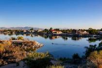 An early-morning a kayaker paddles through Colorado River that flows along Needles, separating ...