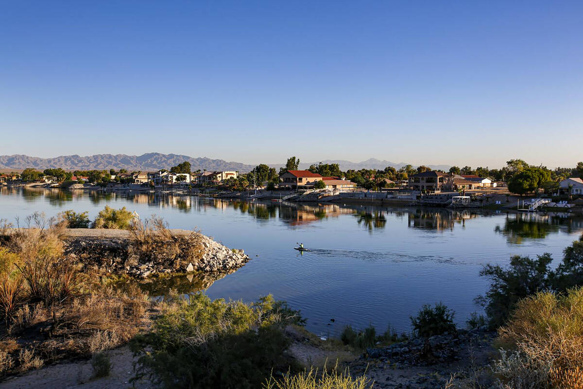 An early-morning a kayaker paddles through Colorado River that flows along Needles, separating ...