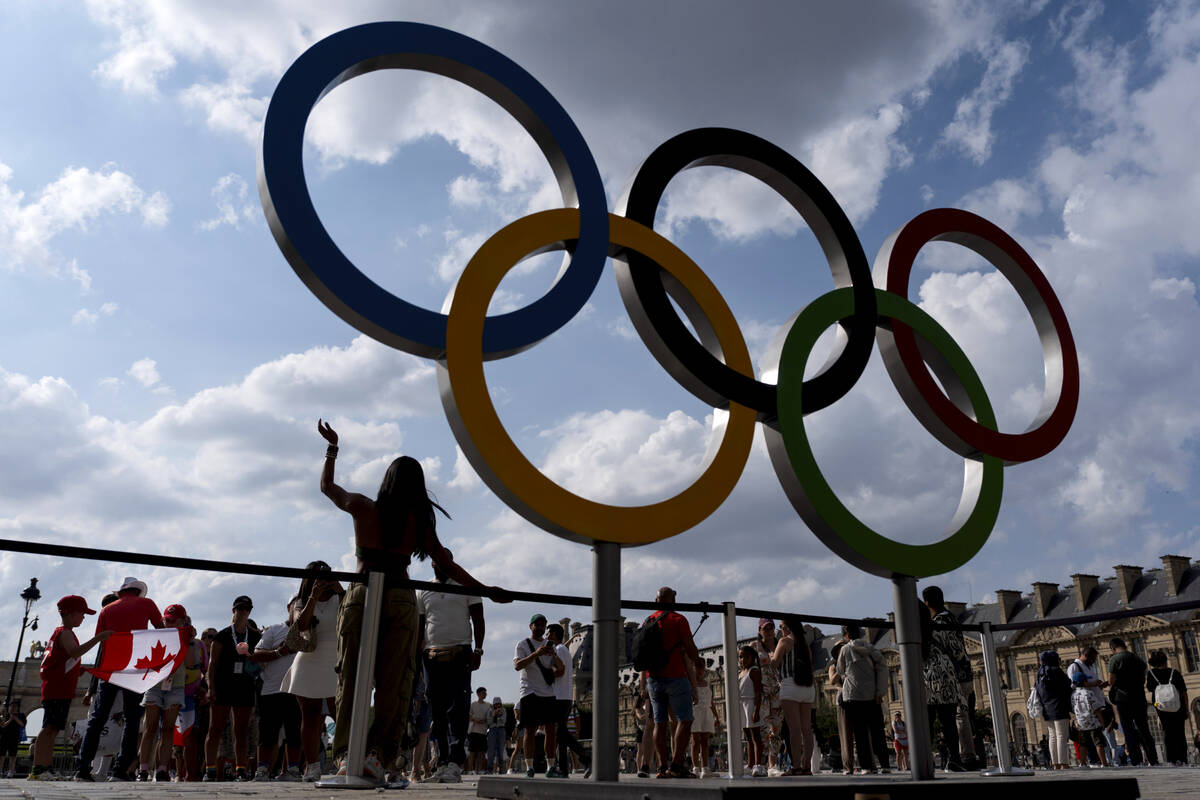 The public lines up to have their picture taken with the Olympic rings in front of the Louvre m ...