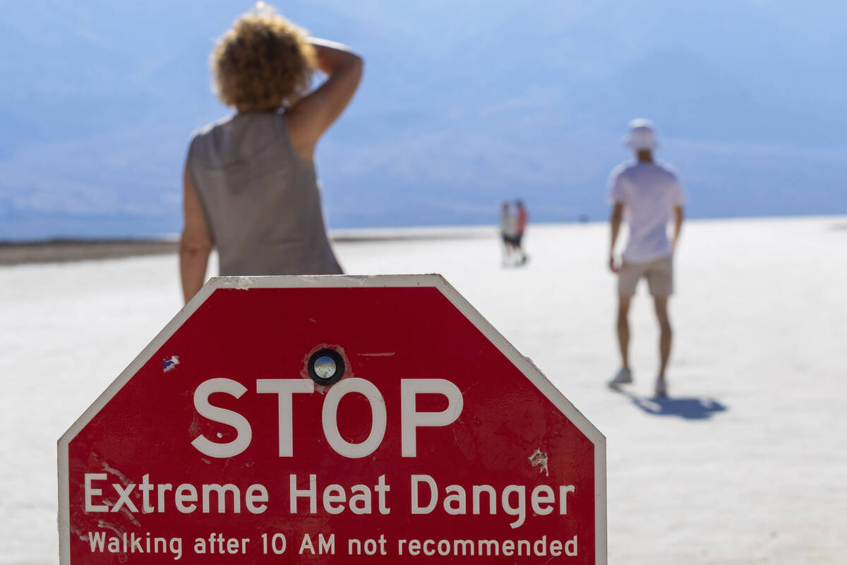 A person wipes sweat from their brow at Badwater Basin in Death Valley National Park, Calif., J ...