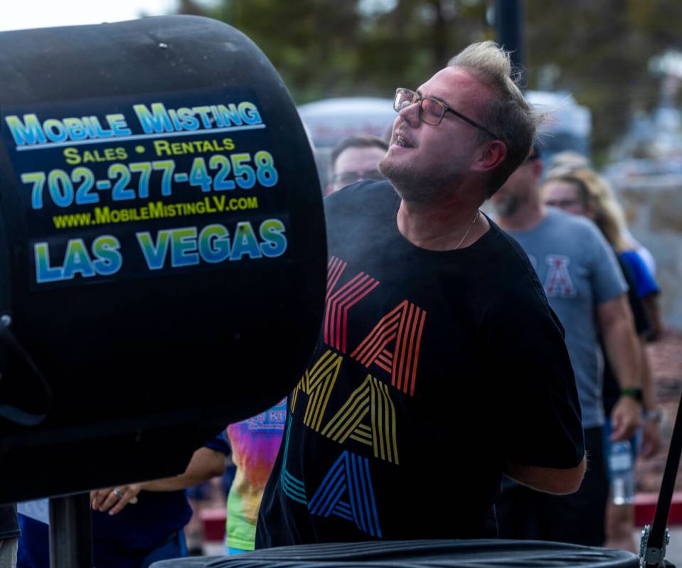 Attendees sneak a quick misting while waiting in the sun to be screened for entry as Vice Presi ...