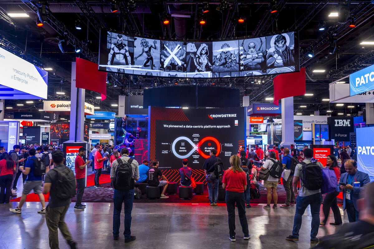 Attendees listen to a talk and wander past the Crowdstrike display during the Black Hat convent ...