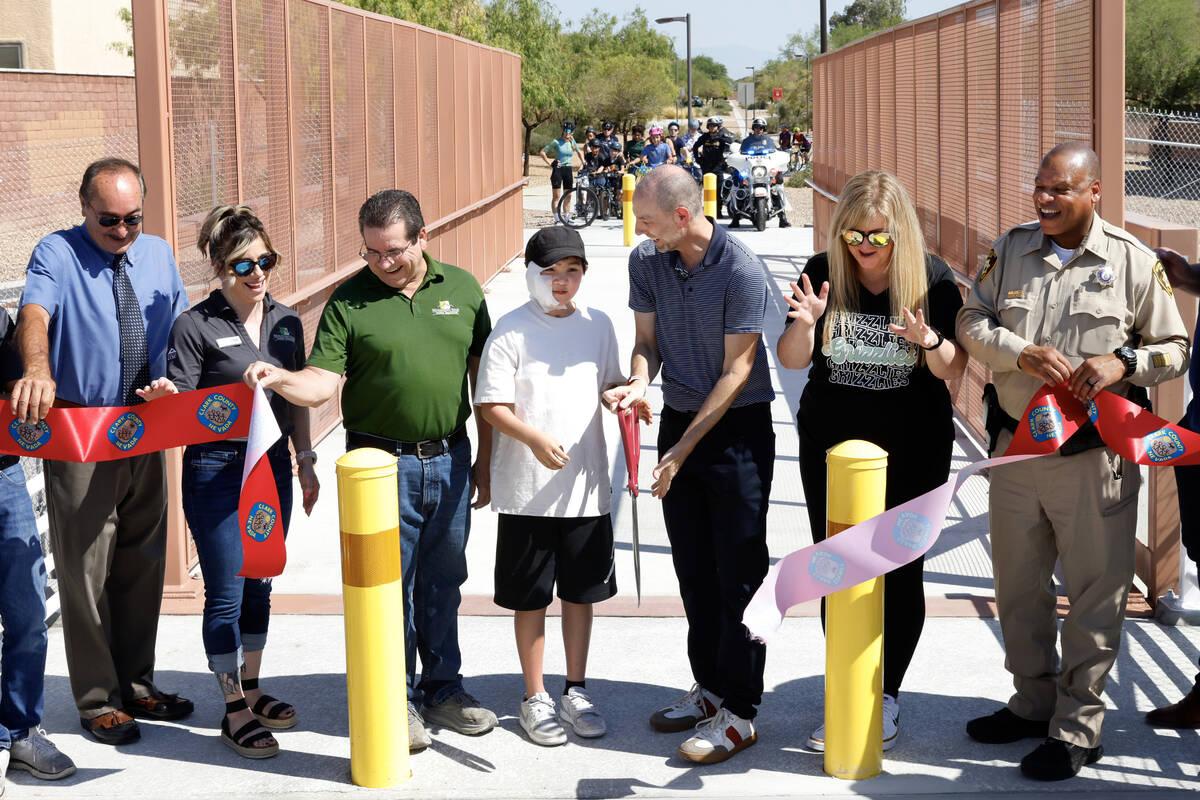 Rayan Kim, 12, assists Clark County Commissioner Justin Jones, center, in a ribbon cutting cere ...