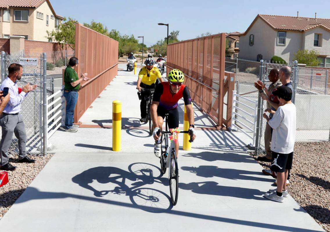 A rider and Metro police officers on motorcycle cross the new pedestrian and bicycle bridge nea ...