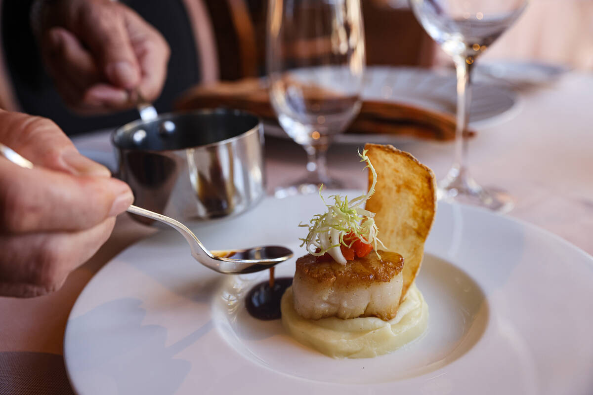 Chef Julian Serrano spoons out jus de veau on the pan seared U-10 day boat scallop at Picasso a ...