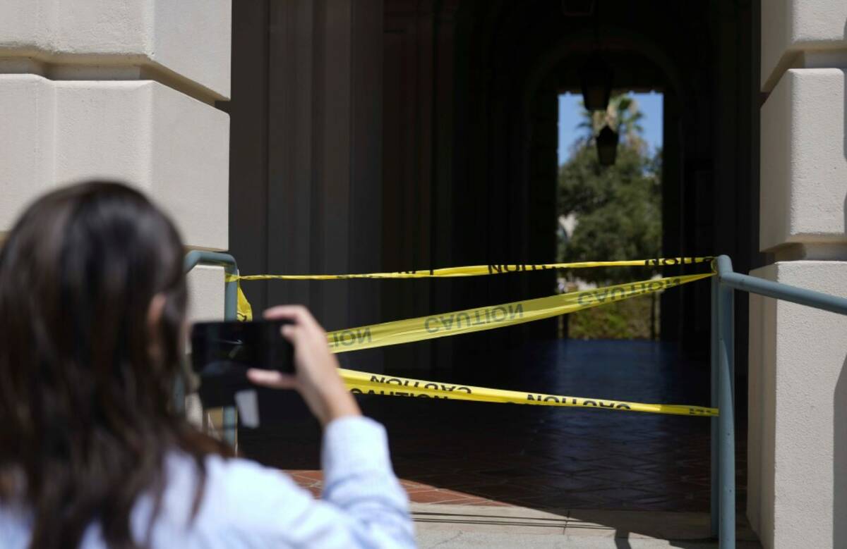 A passerby takes a photo of police caution tape closing off a part of Pasadena City Hall on Mon ...