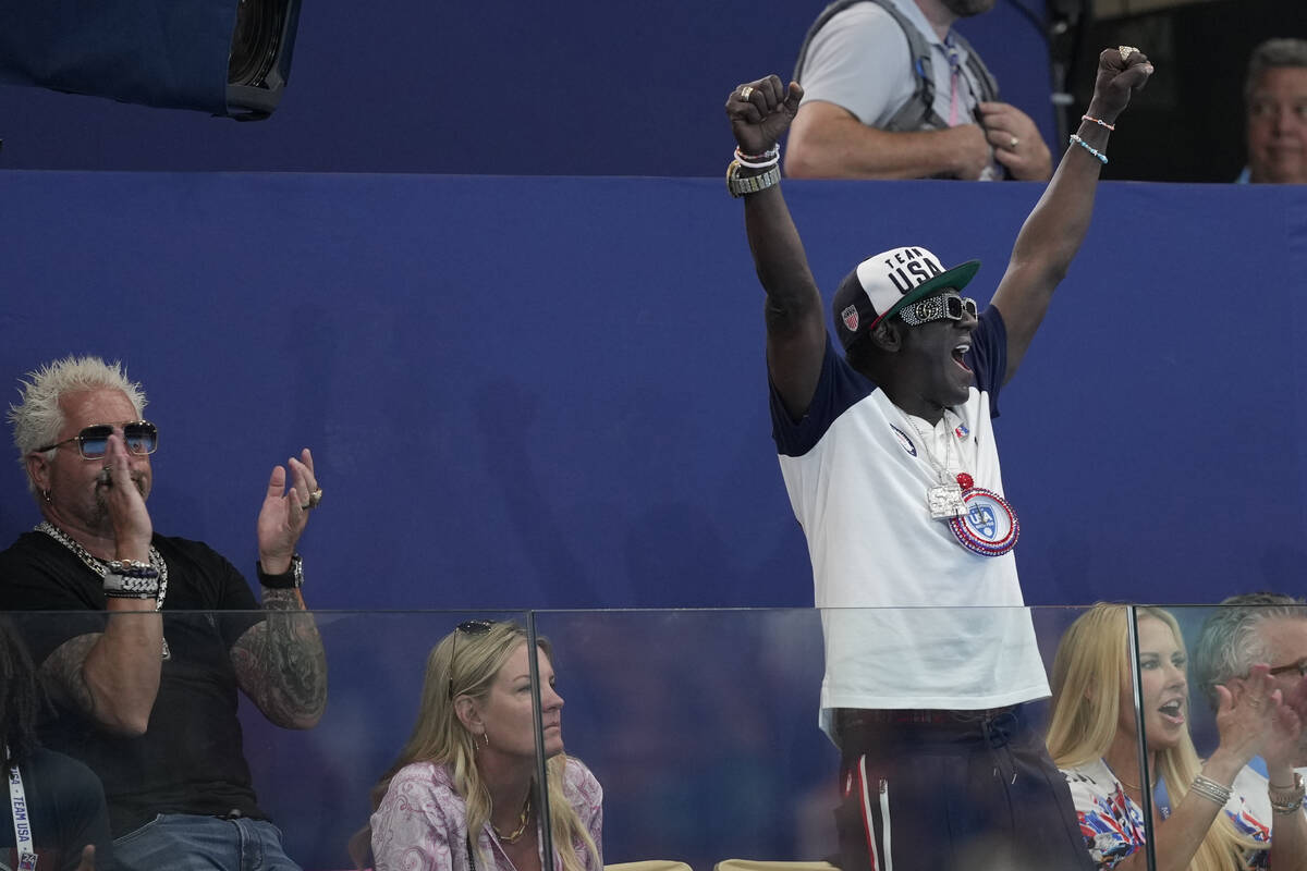 Guy Fieri, left, and Flavor Flav, stand, cheer during a women's water polo Group B preliminary ...