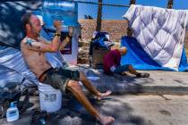 Homeless man Milton John Scott III pours a jug of water on his head to escape the heat and wash ...