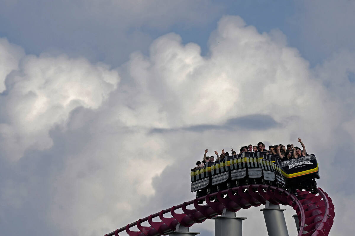 FILE - People ride on the Mamba roller coaster at Worlds of Fun theme park as storm clouds buil ...