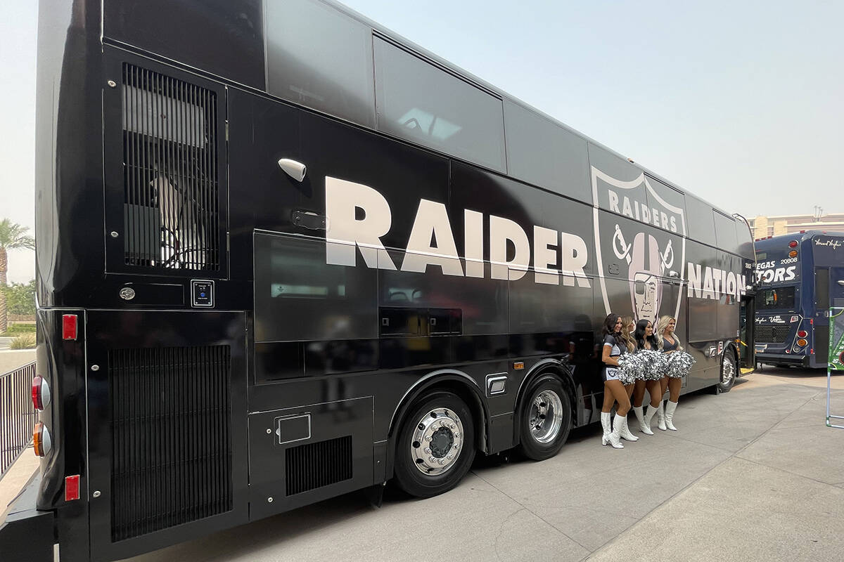 Three Raiderettes stand in front of RTC bus decked out in a Raiders wrap that is part of the RT ...