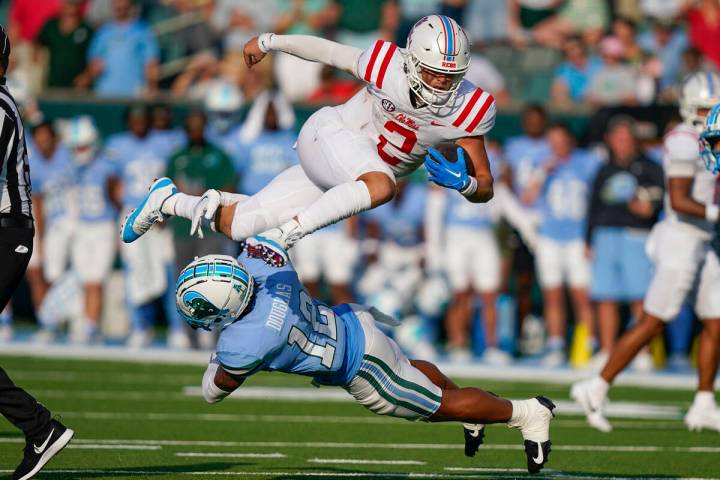 Mississippi quarterback Jaxson Dart (2) carries for a first down over Tulane defensive back DJ ...