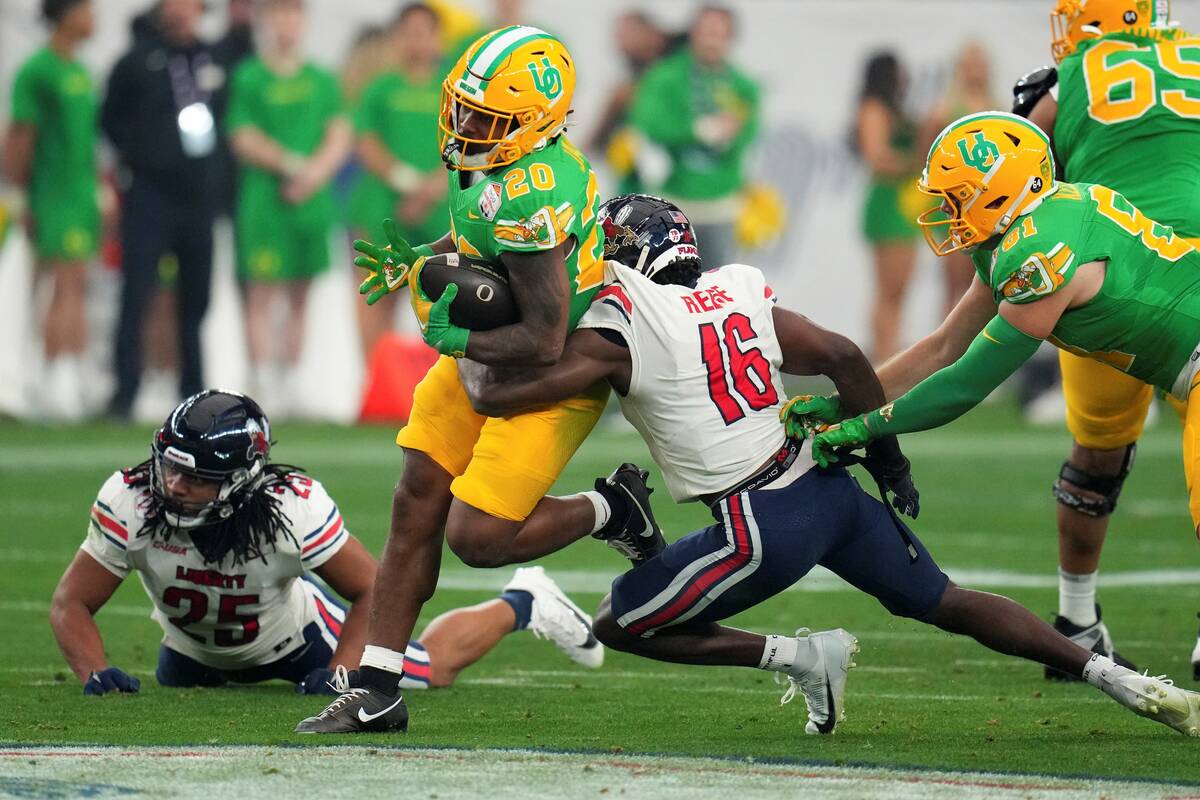 Oregon running back Jordan James (20) is tackled by Liberty safety Quinton Reese (16) during th ...