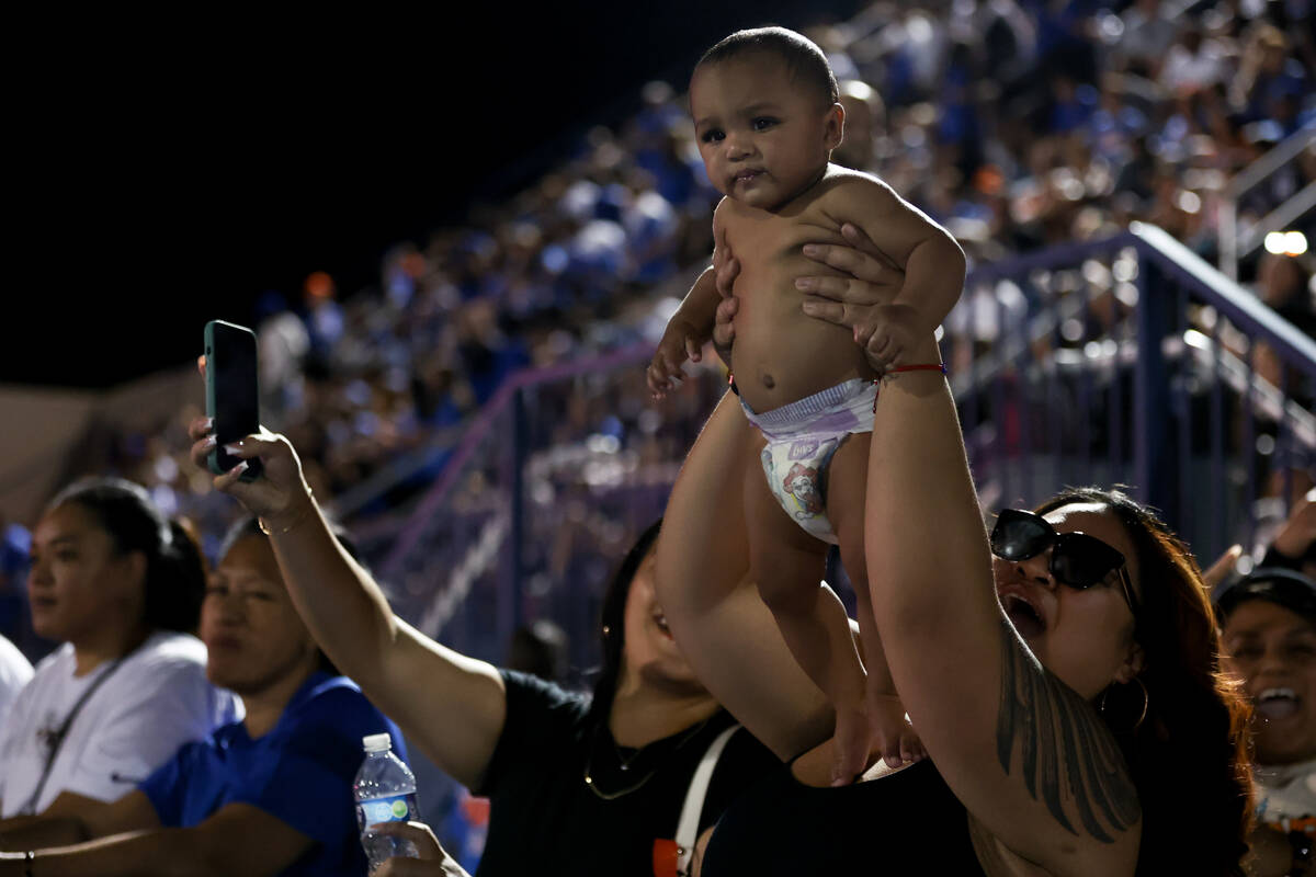 A Bishop Gorman fan holds up her baby as the team is winning during the second half of a high s ...