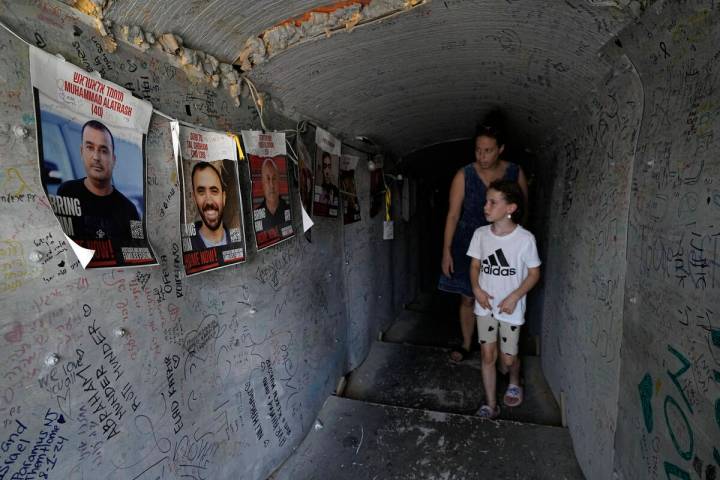 A woman and child walk through a replica of a tunnel used by Hamas militants in the Gaza Strip, ...