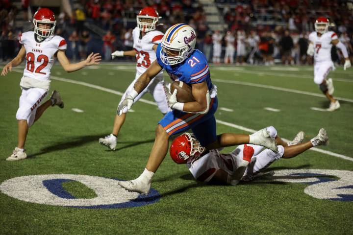 Bishop Gorman running back Jonathan Coar (21) runs through an attempted Kahuku tackle during th ...