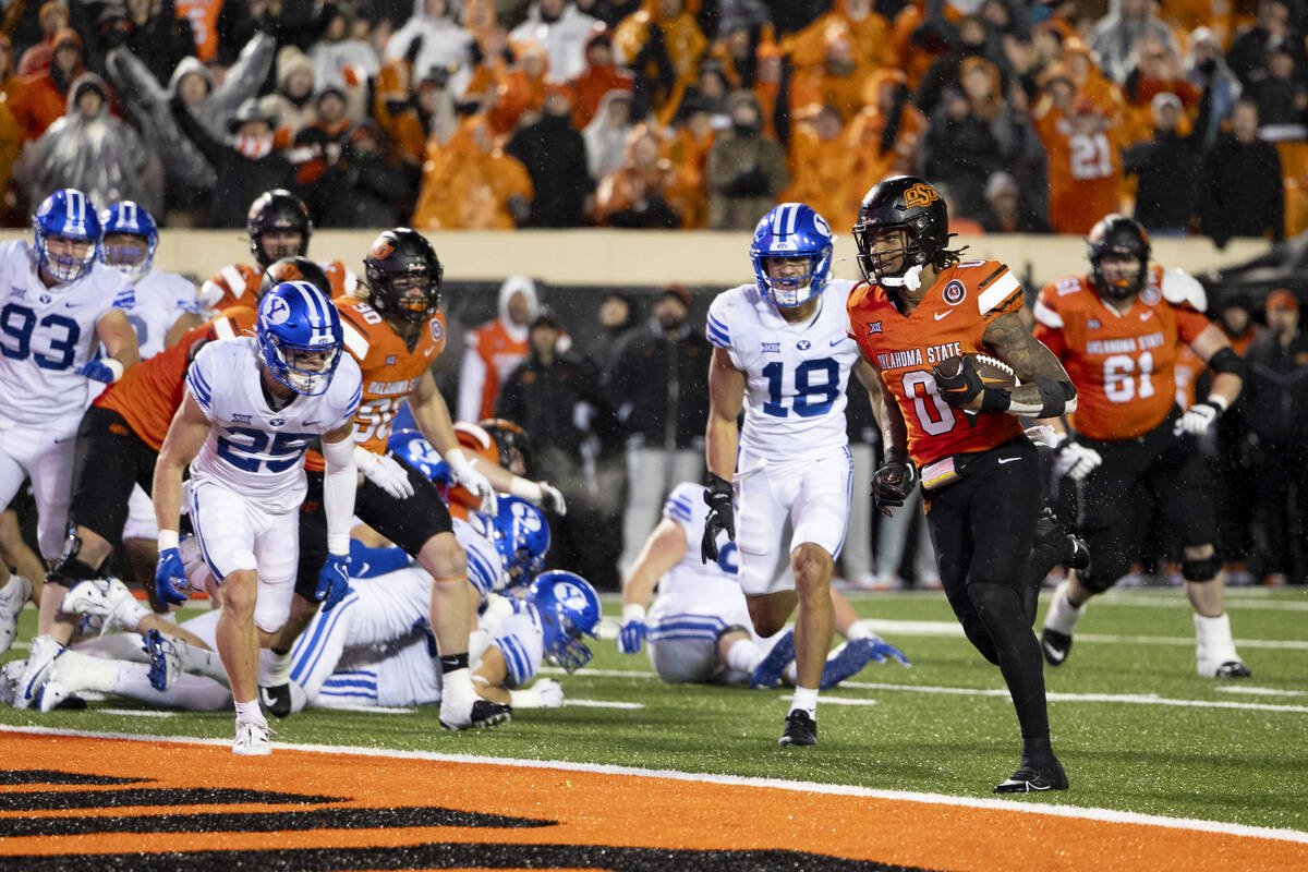 Oklahoma State running back Ollie Gordon II (0) runs past BYU linebacker Ace Kaufusi (18) and s ...