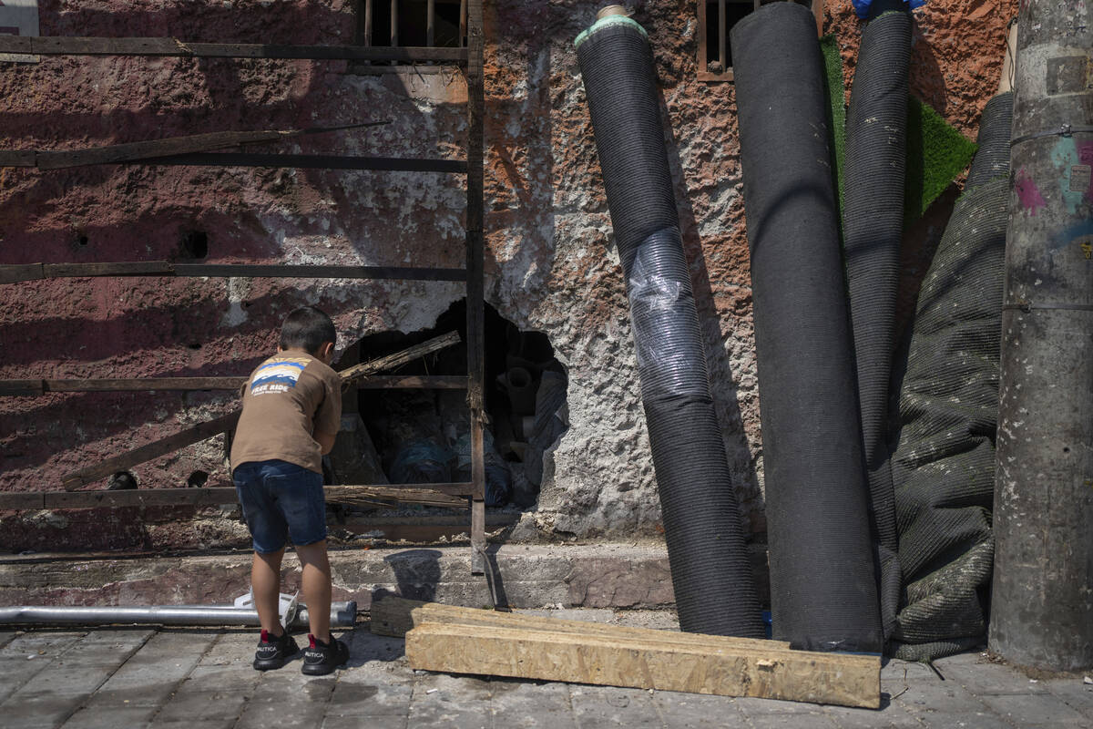 A child looks at a hole in a wall at the scene of a bomb explosion in Tel Aviv, Israel, Monday, ...