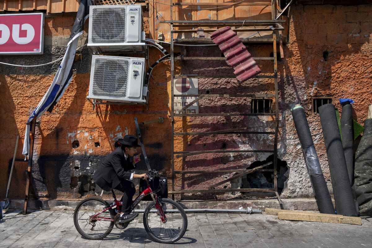 A boy rides a bicycle past the damage after a bomb explosion in Tel Aviv, Israel, Monday, Aug. ...