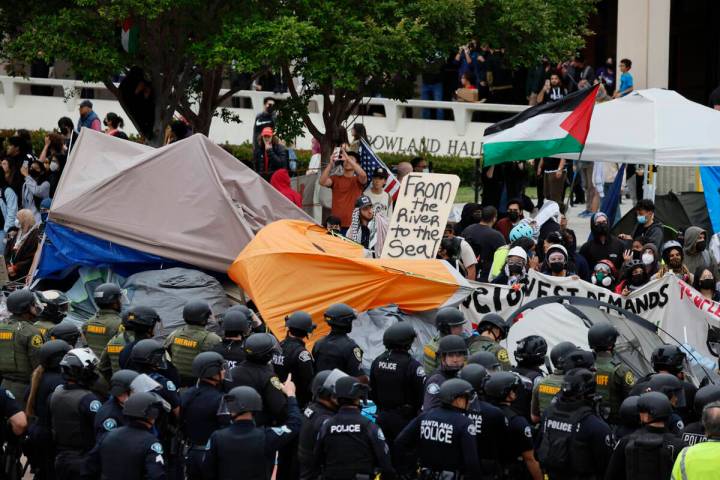 Pro-Palestine demonstrators face off with multiple police agencies forming a containment line, ...