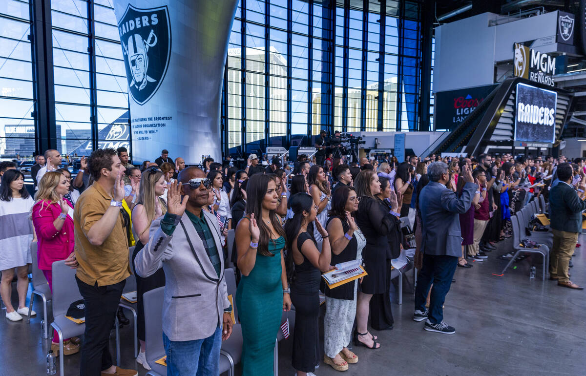 Candidates raise their hands for the Oath of Allegiance during a naturalization ceremony at All ...