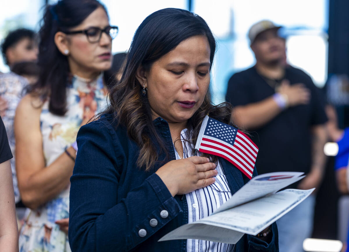 Candidate Rosalyn Tuggle stands with others for the Pledge of Allegiance during a naturalizatio ...