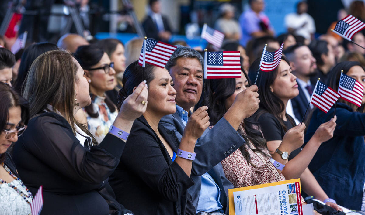 New citizens wave flags during a naturalization ceremony at Allegiant Stadium on Tuesday, Aug. ...