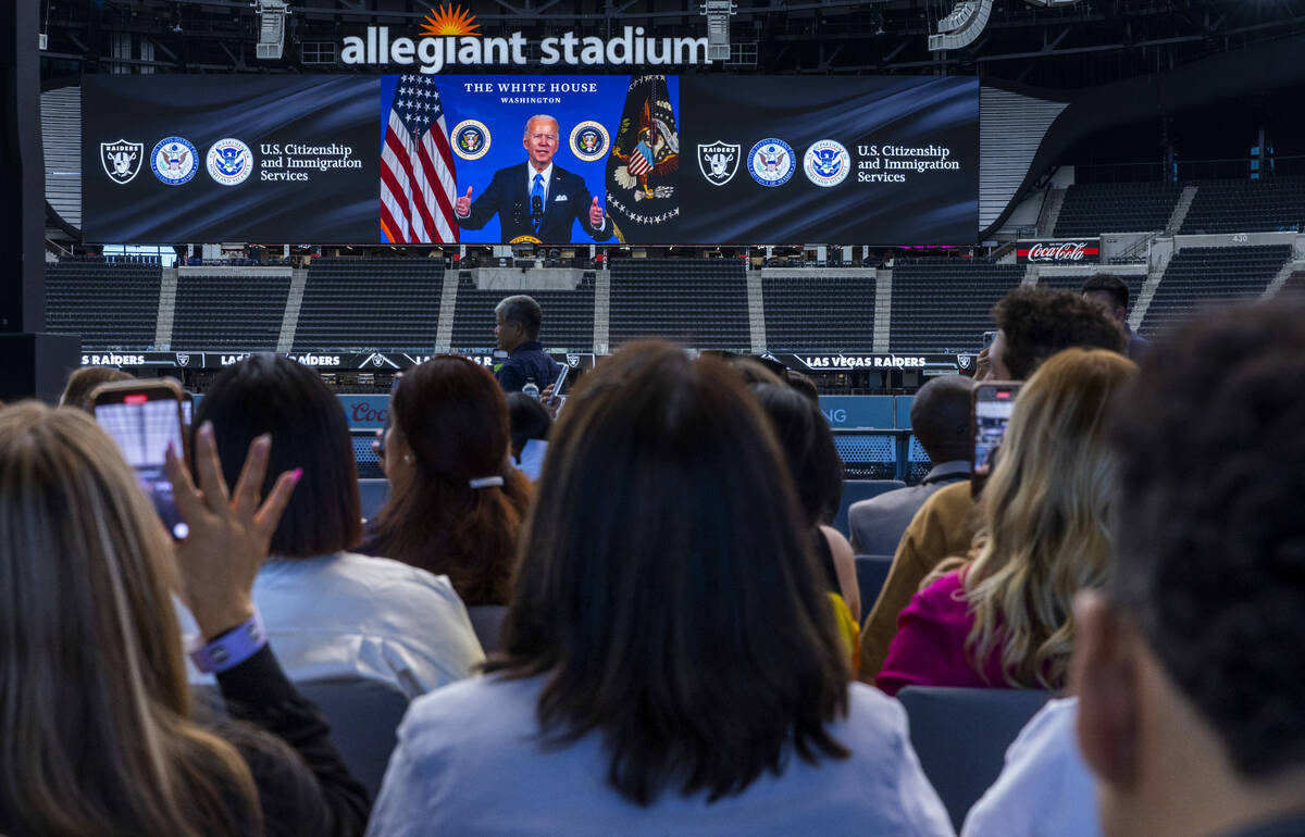 President Joe Biden is broadcast on a message to the new citizens during a naturalization cerem ...